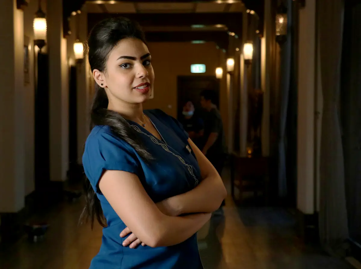 A confident healthcare worker in blue scrubs standing in a corridor